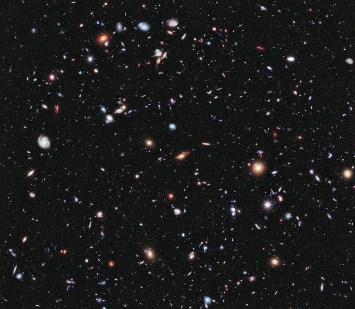 A long-exposure image of a tiny patch of apparently empty sky, crowded with thousands of faint distant galaxies of many shapes and colours.